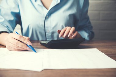 İş kadını el dokümanı ve hesap makinesi ofis masasında.