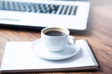 Not defterinde bir fincan kahve ve masada klavye.