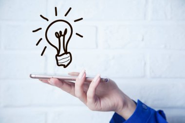 İş kadını, ekranında ampul olan akıllı telefon.