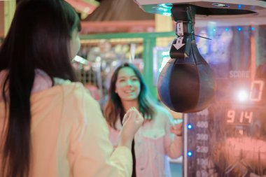 En iyi arkadaşlar lunaparkta kaynaşıyor. Mutlu Asyalı Arkadaşlar, ay parkında boks torbasına vuruyor. Arkadaşlık, gençlik ve tatil kavramı. Resim