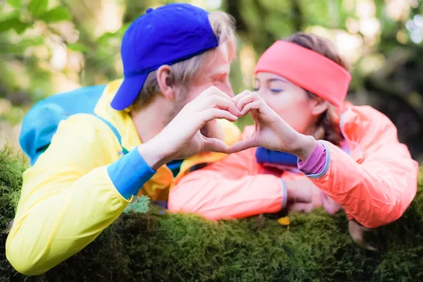 Man and woman having a rest,.they stop to make a romantic heart with hands. Hiking and healthy lifestyle concept - Image