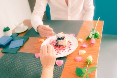 Beyaz tabakta kızılcık soslu cheesecake. Yıldönümünde veya San Valentin 'de pasta yiyen bir çift. Eline odaklan - Resim