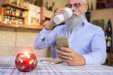 Son sınıf öğrencisi kahve içerken akıllı telefon uygulaması kullanıyor. Yaşlı adam yeni moda teknolojisini kullanıyor. Yaşlı yaşam tarzı konsepti. Eline odaklan - Görüntü