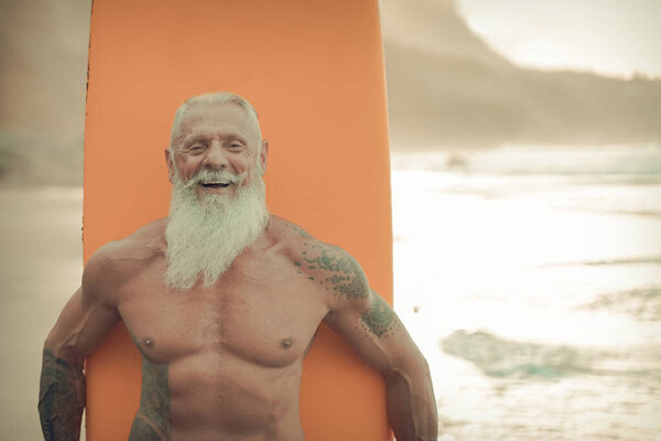 Старший мужчина с апельсиновой доской. Счастливый старик, развлекающийся экстремальным спортом. Радостная пожилая концепция - Изображение
