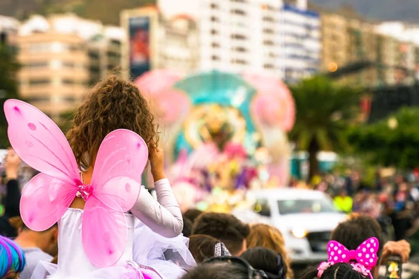 İnsanlar karnaval partisine bakıyor. Karnaval partisinde pembe melek gibi giyinmiş güzel bir kız. Odaklanmamış arkaplan - Resim