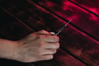 Ahşap arka planda bıçaklı bir şırınga tutan adam.