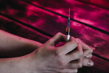 Siyah arka planda aşısı olan bir şırınga tutan bir adam.