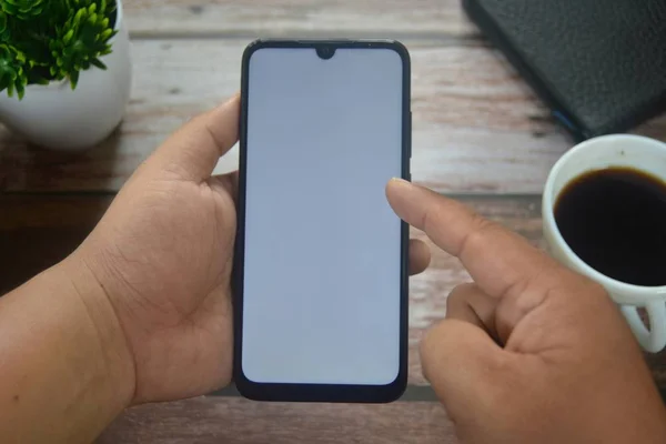Eller boş ekranda ahşap masadaki akıllı telefondan.