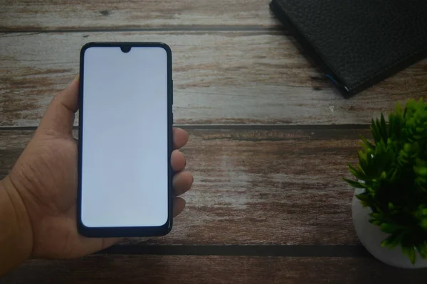 Eller boş ekranda ahşap masadaki akıllı telefondan.