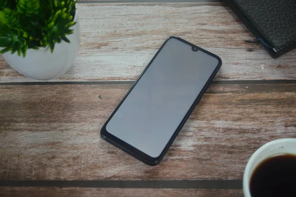 Eller boş ekranda ahşap masadaki akıllı telefondan.