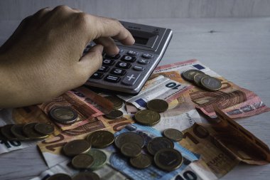 Yukardan görünen hesap makineli Euro ve sikkeler. Hesap makinesini kullanan el.