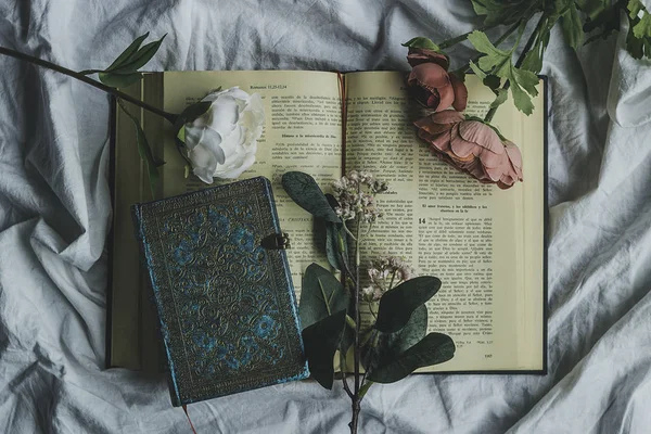 Open bible surrounded by decorative flowers and an intense blue notebook to write down