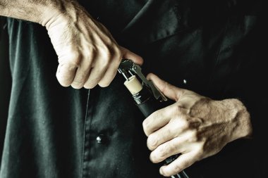 Erkek eller şarap şişesini açıyor.