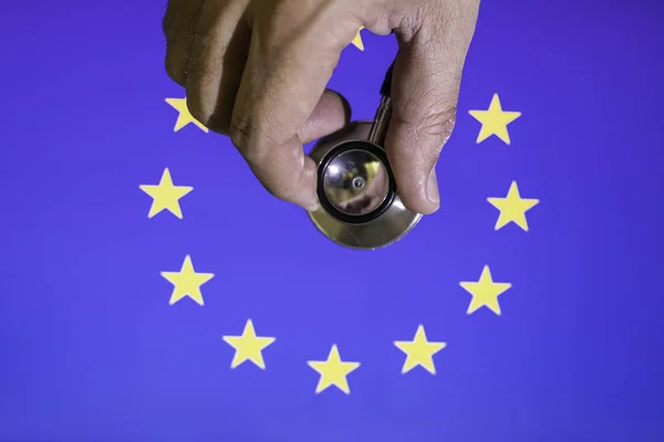 Hand with stethoscope auscultating European Community flag Conceptual Covid-19 crisis, reconstruction europe