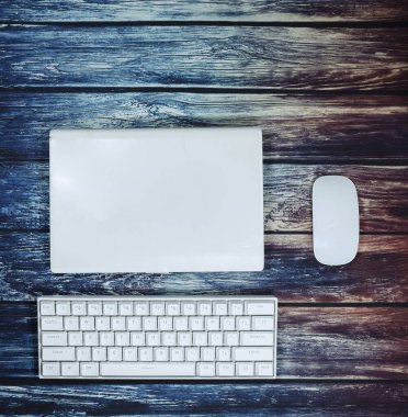 Beyaz klavyeli beyaz dizüstü bilgisayarı ve tahta bir masada beyaz faresi olan ev işi ofisinin minimalist düzeni.