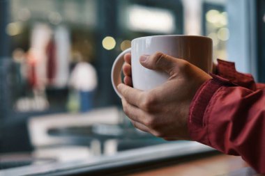 Holding a cup of coffee with blurry background