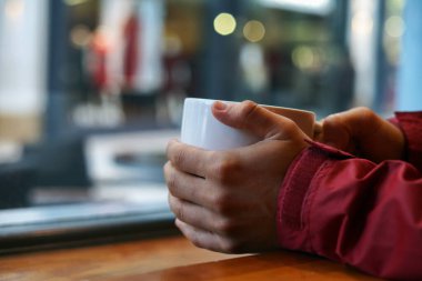 Holding a cup of coffee with blurry background