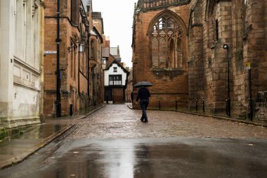 Coventry Katedrali yakınlarındaki eski dar bir sokakta yürüyen bir adam.