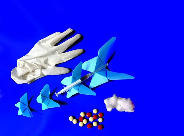 Strzykawka, rękawica lateksowa i pigułki na niebieskich motylach z niebieskim tłem. koncepcja medyczna — Zdjęcie stockowe