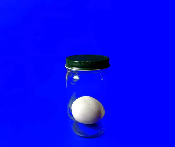 Яйце всередині скляної банки на синьому фоні. концепція здорової їжі — стокове фото