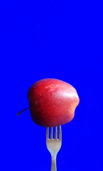 Garfo em uma maçã em fundo azul. conceito de alimentação saudável — Fotografia de Stock