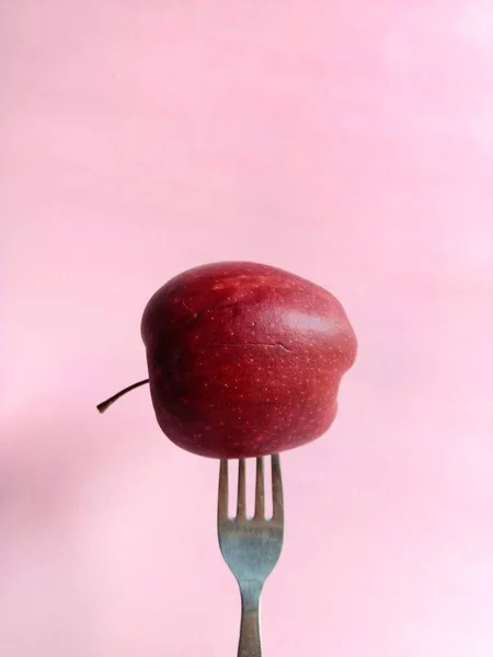 Garfo em uma maçã em fundo rosa. conceito de alimentação saudável — Fotografia de Stock