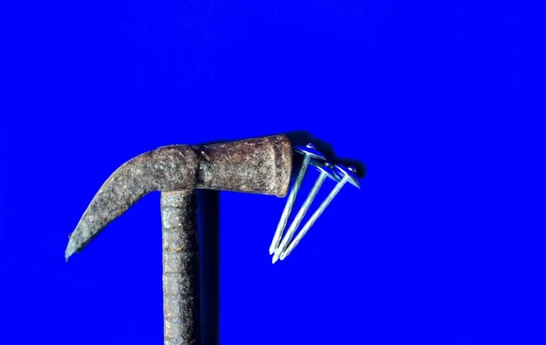 Steel hammer with nails on blue background. construction concept — Stock Photo, Image