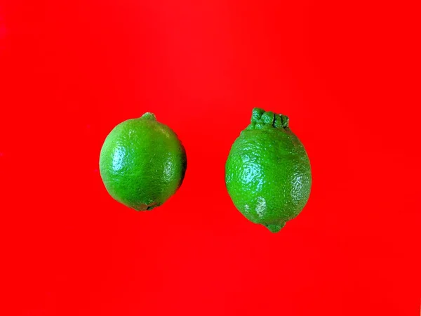 Organic Green Lemons Red Background — Stock Photo, Image