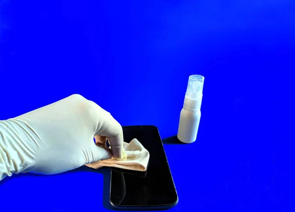 Ręka Białą Rękawicą Czyszcząca Smartfona Niebieskim Tle — Zdjęcie stockowe