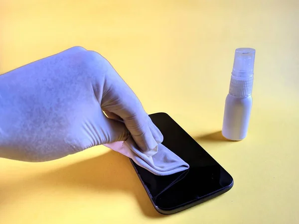 Ręka Białą Rękawicą Czyszcząca Smartfona Żółtym Tle — Zdjęcie stockowe