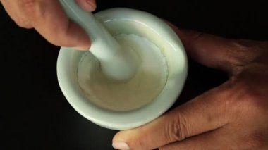 Eczacı elini havana beyaz ilaç tozu karıştırıyor.