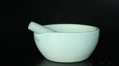 Beyaz toz, yiyecek, spa, bitkisel ve ilaç hazırlıkları için siyah arkaplan üzerine havan ve kürek döker.