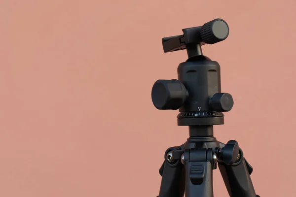 Pembe duvar arka planında siyah tripod