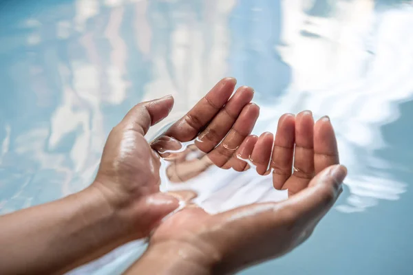 Manos tapadas parcialmente sumergidas en agua potable azul clara - Manos mojadas levantadas de un manantial de agua dulce — Foto de Stock