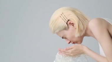 Kadın temiz yüzünü suyla yıkıyor. Genç yetişkin kız yüzünü suyla yıkıyor. Ağır çekim. Güzellik tedavileri. Cilt bakımı. Sağlıklı deri konsepti. Profil portresi. 