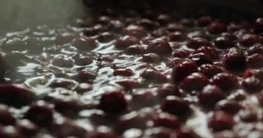 Kiraz reçeli pişiriyorum. Reçel pişirme. Mutfak spatulasıyla leğen kemiğinde kiraz reçeli pişiriyorum. Adam kiraz reçelini karıştırıyor. Ağır çekim. 4k görüntü. 