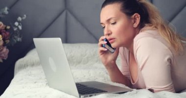 Yetişkin bir kadın evden telefonla arıyor. Kanepede uzanmış cep telefonuyla konuşan yetişkin bir kadın. Beyaz bir kadın cep telefonuyla konuşuyor. Yaşam tarzı konsepti. Huzursuz kadın sorunlu bir telefon aldı..    