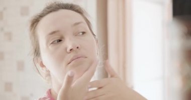 Yetişkin bir kadın boyun masajı yapıyor. Güzel bir kadın yaşlanmayı önleyen yüz masajı yapar. 35 yaşında beyaz bir kadın teniyle ilgileniyor. Güzellik tedavileri. Vücut terapisi. Cilt için sağlıklı bir sabah prosedürü