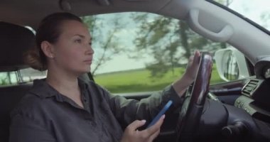 Arabayı kadın kullanıyor. Arabadaki mutlu kadın telefonda konuşuyor. Arabayı güzel, yetişkin, gülümseyen bir kadın kullanıyor. Beyaz yetişkin bir kız araba sürerken cep telefonuyla konuşur. Gerçek zamanlı. İçeride..