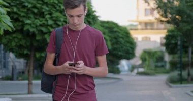 Parkta cep telefonu kullanan bir genç. Dışarıda cep telefonu kullanan genç bir adam. Cep telefonu olan genç bir çocuk. Şehir manzarası. Yakışıklı adam akıllı telefon kullanıyor. 4 bin. Gerçek zamanlı..