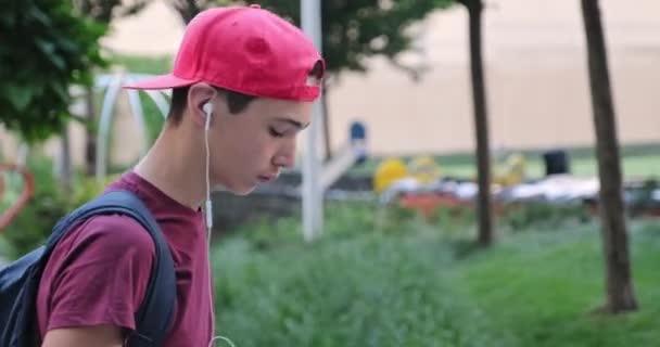 Adolescente Caminando Calle Escuchar Música Los Auriculares Estudiante Con Gorra — Vídeo de stock