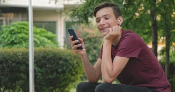 Adolescente Utilizzando Telefono Cellulare Nel Parco Giovanotto Sorridente Che Usa — Video Stock