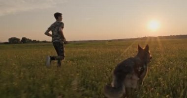 Günbatımında genç bir köpek ile doğada koşuyor. 15 yaşında bir çocuk bir Alman çoban köpeğiyle koşuyor. Sahada köpekli bir genç. Beyaz adam çayırda evcil hayvanıyla oynuyor. Yavaş çekim