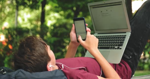 Menino Adolescente Com Laptop Telefone Celular Parque Jovem Usando Celular — Vídeo de Stock