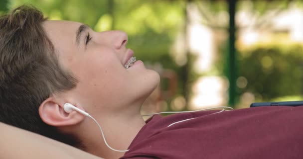 Portrait Adolescent Heureux Dans Des Écouteurs Couchés Sur Banc Dans — Video