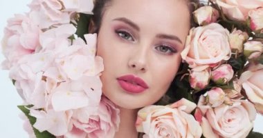 Face with flowers. Beautiful caucasian woman with fresh skin. Closeup female face with flowers. Beauty concept. Skin care. Young girl with natural makeup. 4k. Slow motion