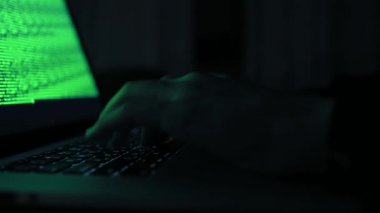 Hacker bilgisayar ağına sızıyor. Karanlık bir odada dizüstü bilgisayarda yazan genç bir insan. Bilgisayarı olan bir bilgisayar korsanı. Soyguncu. Bilgisayar klavyesinde yazı yazan ellerin yakın çekimi. 4k görüntü
