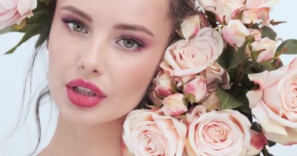 Face with flowers. Beautiful caucasian woman with fresh skin. Closeup female face with flowers. Beauty concept. Skin care. Young girl with natural makeup. 4k. Slow motion
