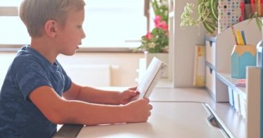 Çocuk evde kitabı okuyor ve yorgunluktan sonra başını masaya koyuyor. Öğrenci çocuk bir kitap okuyor. 8 yaşındaki bir çocuk elinde kitapla masanın üzerinde dinleniyor. Okuldan sonra ev ödevi yapan çocuk. 