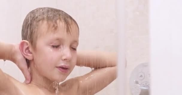 シャワーを浴びている男の子 白人の子供は浴室でシャワーを浴びます 温水の流れの下で男の子を洗う治療 8歳のヨーロッパの子供は髪を水で洗い流しています リアルタイムだ低角度 — ストック動画